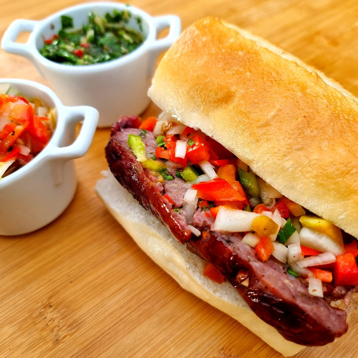 Choripán – Argentinian sausage sandwich with chimichurri and salsa criolla